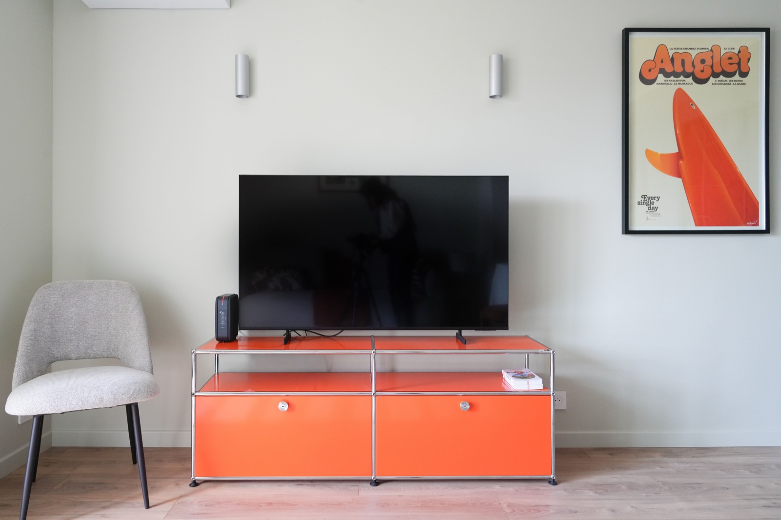 Salon avec meuble USM orange et affiche Anglet surf
